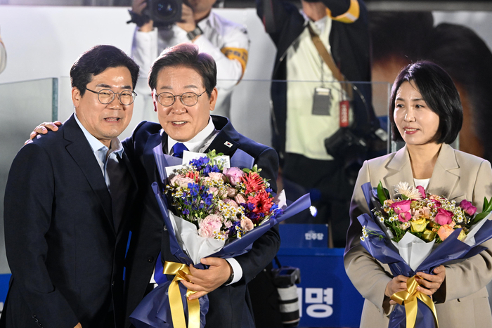 제21대 대통령 당선이 확실시되는 더불어민주당 이재명 대선 후보와 부인 김혜경 여사가 4일 서울 여의도 국회 인근에서 당 주최로 열린 국민개표방송 행사에 참석해 박찬대 상임 총괄선대위원장에게 꽃다발을 받고 있다. 연합뉴스