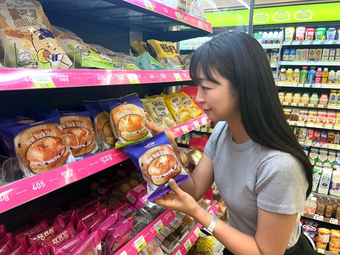 모델이 크래프트 크림치즈 베이글을 살펴보고 있다.