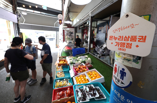 정부가 민생회복 소비쿠폰 1차 지급계획을 발표한 지난 7월 서울의 한 전통시장 점포에 기존 골목경제 소비 활성화를 위한 온누리상품권 가맹 팻말이 붙어 있다.