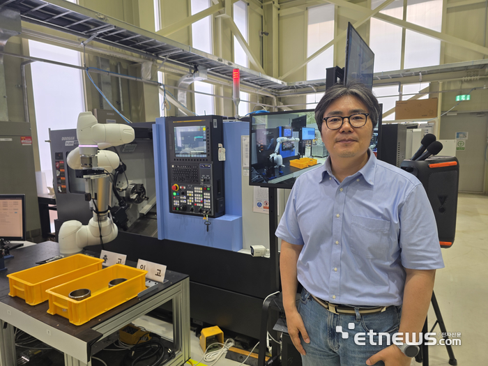 황정훈 KETI 지능로보틱스연구센터장이 인공지능을 탑재한 로봇팔이 구형 공업용 가공기계를 조작하는 앞에서 설명하고 있다. (사진=김영호 기자)