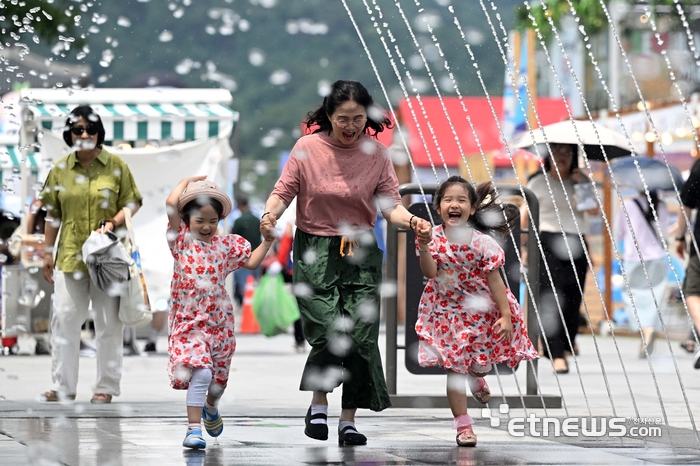 전국 대부분의 지역에 폭염 특보가 발령된 지난 7월 23일 서울 종로구 광화문광장 분수대에서 한 가족이 분수 터널을 지나고 있다. 기상청은 이날 서울 낮최고기온이 33도에 이를 것으로 예보했다. 김민수기자 mskim@etnews.com