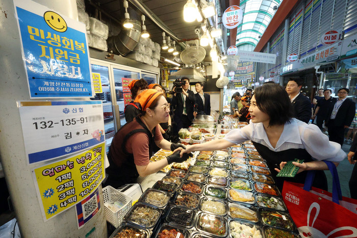 김혜경 여사가 25일 인천 계양산전통시장을 방문해 한 매장에서 상인과 인사하고 있다. 연합뉴스