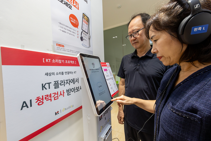 KT플라자에 방문한 고객이 KT 직원으로부터 AI 청력검사 키오스크의 사용법에 대한 설명을 듣고 있다.