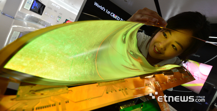 접고 구부릴 수 있는 플렉시블 디스플레이 시대가 도래했다. 웨어러블 기기 등 사물인터넷(IoT) 기반 융합 제품 혁신에 중요한 역할을 담당할 것으로 예상된다. LG디스플레이 직원이 최근 개발에 성공한 곡률반경도 30R을 구현하는 18인치 플렉시블 OLED를 보여주고 있다. 2014.09.19 / 김동욱기자 gphoto@etnews.com
