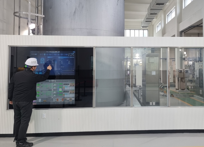 한국수자원공사 관계자가 경기도 화성에 있는 AI 정수장에서 약품주입동에 구현된 '스마트 미러'(터치형 화면)를 보며 정수처리에 필요한 약품주입 자율공정 현황 등을 살펴보고 있다. 사진 출처 : 한국수자원공사