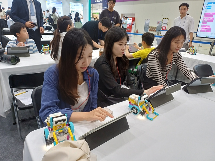 2025 에듀테크 코리아 페어에 참가한 교사와 초등학생들이 AI 로봇 프로그램 체험을 하고 있다. (사진=마송은 기자)