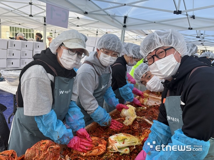 JW 임직원들이 지난 1일 과천시민회관 시계탑 광장에서 열린 '2025년 모두가 나누는 김장축제'에서 김장을 담그고 있다.