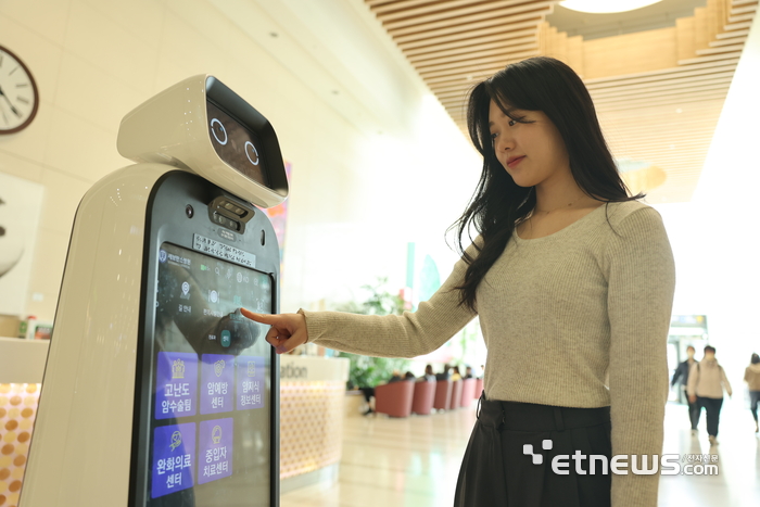 내원객이 클로이 안내로봇으로 길찾기를 하고 있다.