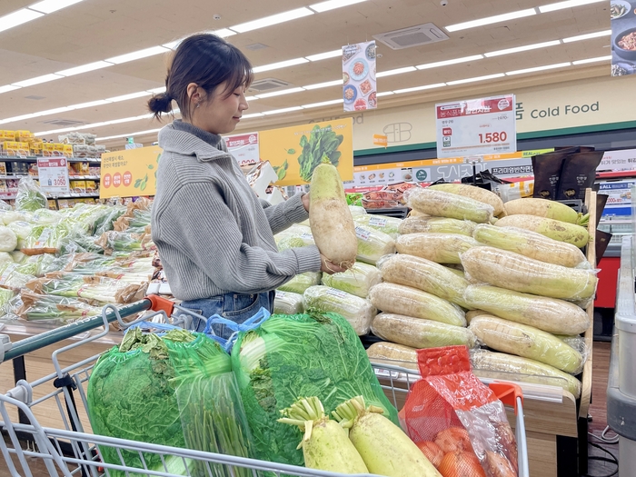 GS더프레시 점포 앞에서 모델이 배추를 살펴보고 있다