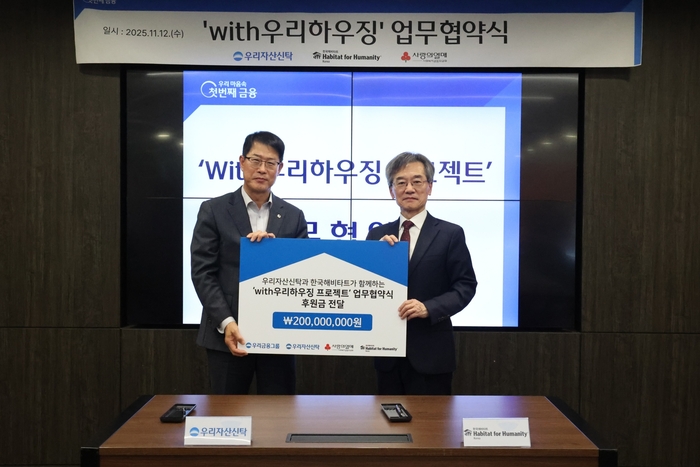김범석 우리자산신탁 대표이사(왼쪽)와 이광회 한국해비타트 사무총장이 지난 12일 우리자산신탁 본사에서 열린 'with우리하우징' 업무협약식에서 기부금 전달식을 갖고 기념사진을 촬영했다.