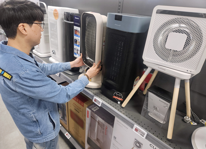 이마트 난방가전 매대에서 직원이 상품을 살펴보고 있다.