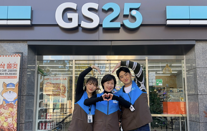 GS25의 OFC(영업관리자)와 가맹 경영주가 매장 앞에서 하트를 그리고 있다