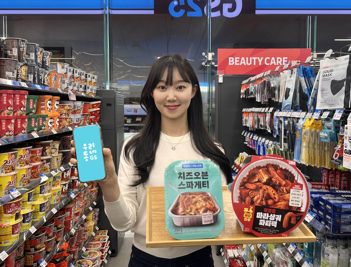 GS25에서 모델이 마라샹궈파티팩, 치즈오븐스파게티를 들고 포즈를 취하고 있다.