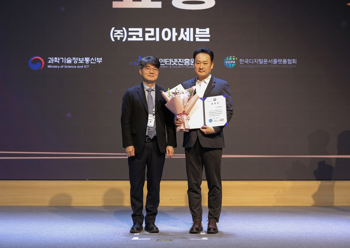 지난 1일 서울 SC컨벤션센터에서 개최된 '2025 전자문서 산업인의 날' 행사에서 문대우 세븐일레븐 디지털혁신부문장(오른쪽)이 부총리 겸 과학기술정보통신부장관 표창 수상 후 엄열 과학기술정보통신부 국장과 기념촬영을 하고 있다.