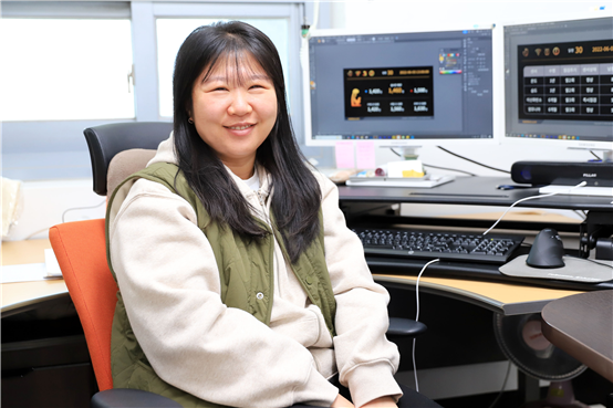 기업협력프로젝트에 참여한 교육생 송아랑 씨가 업무 중 자신의 자리에서 카메라를 향해 환하게 웃고 있는 모습.