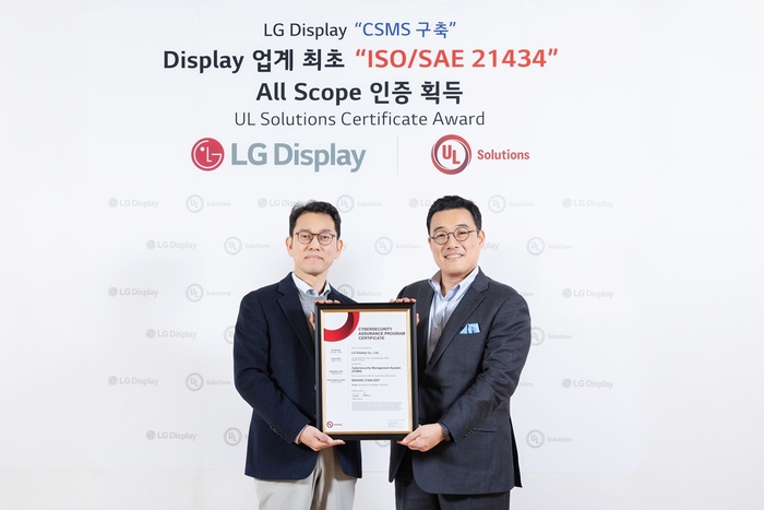 권극상 LG디스플레이 오토사업그룹장(왼쪽)이 정륜 UL솔루션즈 한국지사장으로부터 '자동차 사이버보안 엔지니어링 국제 표준(ISO/SAE 21434)' 인증서를 전달받고 있다. 〈사진 LG디스플레이 제공〉