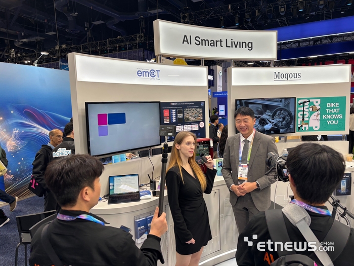 이엠시티 관계자가 CES2026 부스 앞에서 인터뷰를 하고 있다.