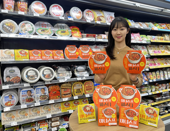 GS25에서 모델이 마녀스프 시리즈 앞에서 포즈를 취하고 있다.