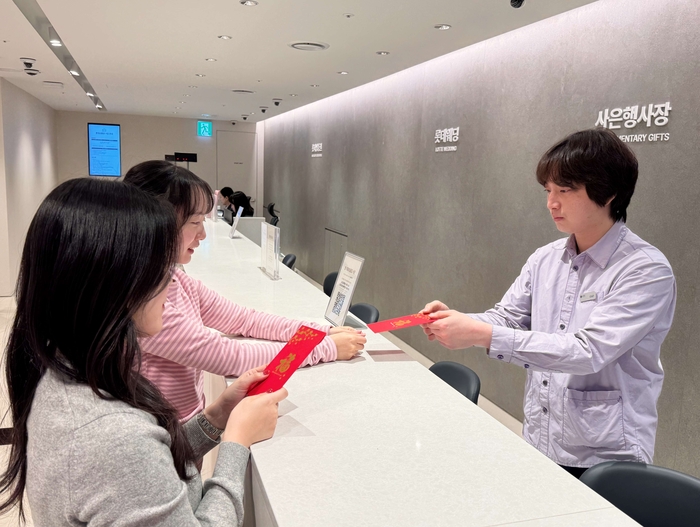 롯데백화점 본점 사은행사장에서 고객에게 춘절 기념 홍바오(붉은 봉투)에 상품권을 증정하고 있다.