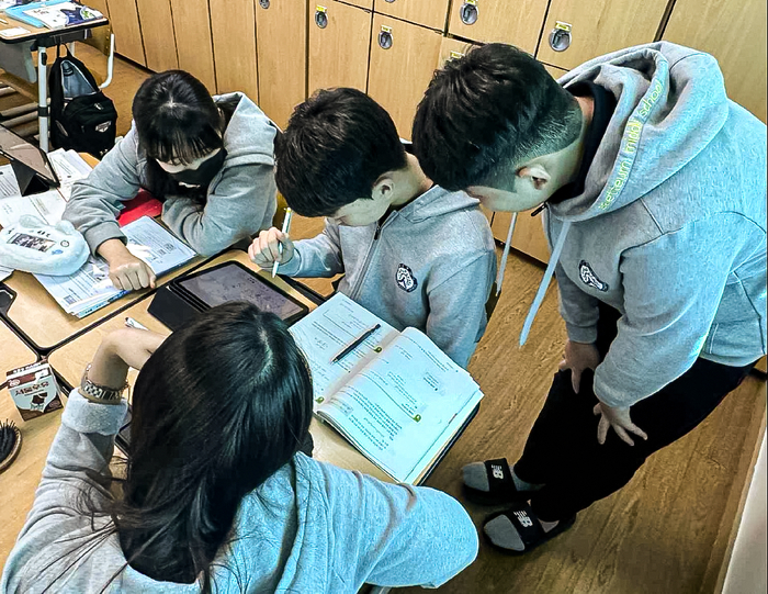 새뜸중학교 학생들이 모둠별로 모여 '레벨퀴즈'를 풀며 서로 설명하고 돕는 협력 학습을 진행하고 있다. AI 코스웨어를 통해 실시간 채점과 수준별 문항 제공이 가능해지면서 교실 내 상호작용이 더욱 활발해졌다. (사진=프리윌린)