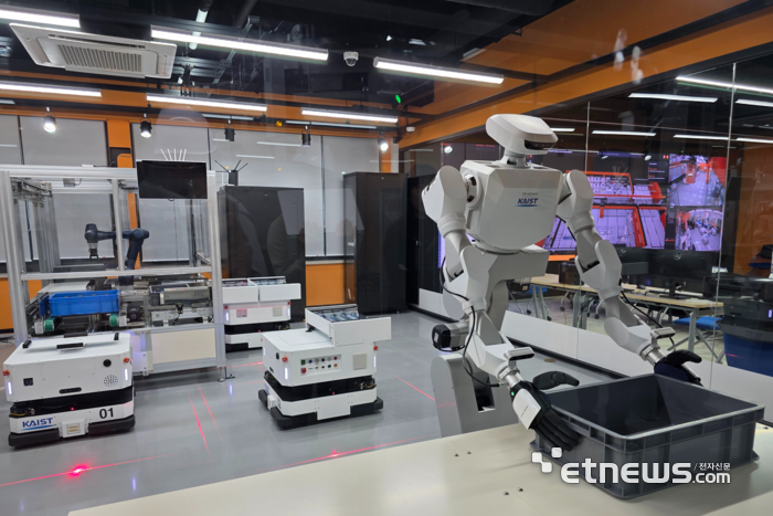 23일 대전 유성 KAIST 피지컬 AI 테스트베드 '카이로스'에서 로봇이 트레이를 운반하기 위해 잡고 있다. 테스트베드 외부 오른쪽 뒤편 화면은 통합 관제 시스템 모니터. ⓒ박종진기자