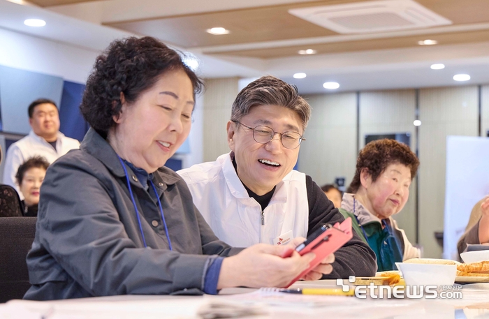 정재헌 SKT 대표이사가 경기도 포천시 관인노인대학에서 어르신 고객의 스마트폰을 살펴보고 대화를 나누고 있다.