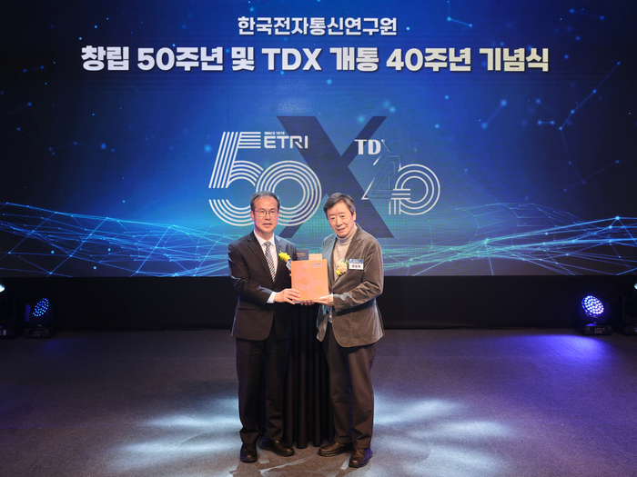 방승찬 ETRI 원장(왼쪽)이 1일, ETRI에서 개최된 창립 50주년 행사에서 양승택 전 정통부장관(전 원장)에게 50년사를 전달하고 있다.