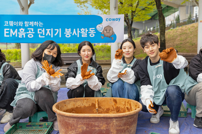 코웨이 임직원 봉사자가 안양천 다목적광장에서 EM흙공을 제작하고 있다.