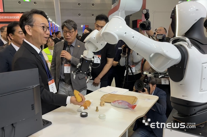 김명주 경상남도 경제부시장이 GSAT 2026 개막식 후 VIP 투어 중 로볼루션 부스에서 로봇과 물건을 주고받는 체험을 했다.