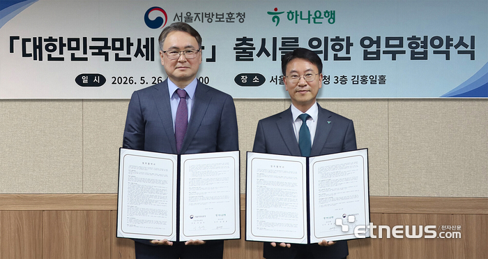하나은행은 지난 26일 오후 서울 용산구 서울지방보훈청에서 호국보훈의 달을 맞아 '대한민국만세 적금' 출시를 위한 업무협약을 체결했다. 이날 협약식에 참석한 김영호 하나은행 리테일그룹 그룹장(오른쪽)이 이승우 서울보훈청장과 함께 협약서를 들고 기념 촬영을 하고 있다. [사진= 하나은행 제공]