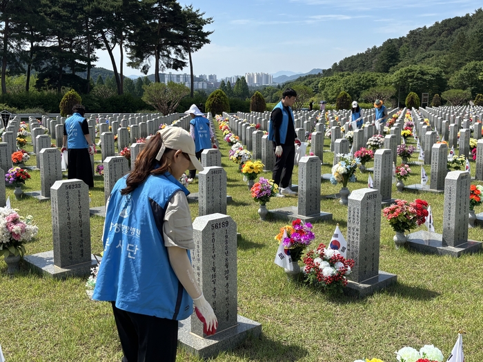 대전자생한방병원 임직원과 대전자생봉사단원들이 국립대전현충원 묘역에서 비석을 정비하고 태극기를 꽂고 있다.