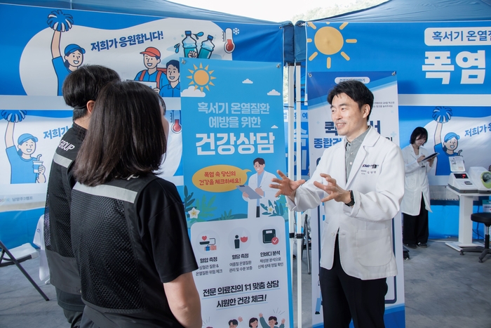 김경연 KMI 직업환경의학센터장(오른쪽)이 지난 11일 경기 남양주2 캠프를 방문해 위탁배송업체 소속 배송기사들에게 혹서기 온열질환 예방을 위한 주의 사항을 설명하고 있다.
