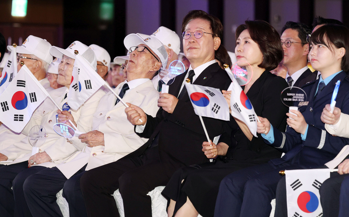 이재명 대통령과 김혜경 여사가 25일 수원컨벤션센터에서 열린 6·25전쟁 제76주년 기념식에서 합창곡에 맞춰 태극기와 응원봉을 흔들고 있다. 연합뉴스
