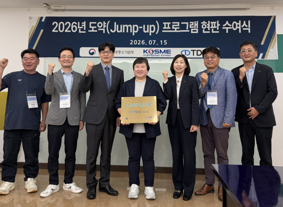 김선미 티디엠 대표(가운데)가 박종찬 광주전남지방중소벤처기업청장(왼쪽 세번째)으로부터 '2026년 도약(Jump-up) 100대 기업' 현판을 전달받은 뒤 기념촬영하고 있다.