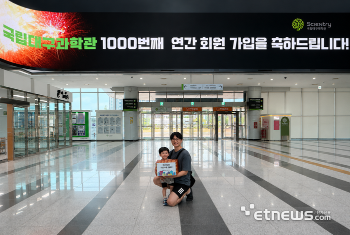 국립대구과학관 연간회원 1000번째 가입자인 이강민 어린이와 아버지가 기념 선물 꾸러미를 들고 기념촬영을 하고 있다.