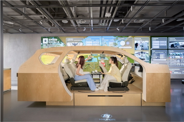 UX 테스트존에 전시된 나무로 만든 스터디 벅에서 방문객이 마주 앉아 대면 모드를 체험하는 모습.