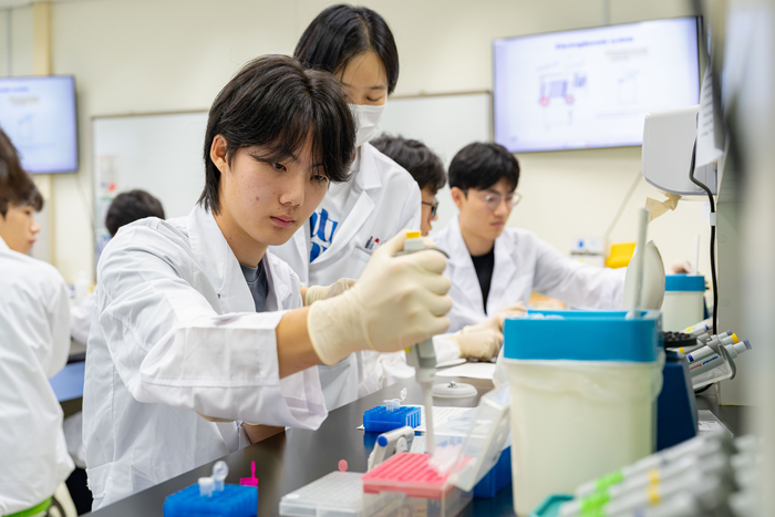 참가자들이 '화학 전공' 실험에서 강사의 설명을 들으며 실험에 참여하고 있다.