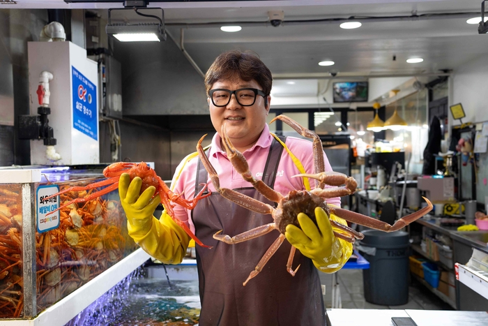 속초관광수산시장 예스수산의 점주가 게를 들어보이고 있다. 〈자료 쿠팡〉