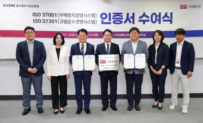 공영홈쇼핑 ISO 37001·37301 통합 인증 수여식에서 엄진엽 중소벤처기업인증원 원장(왼쪽 세 번째), 이일용 공영홈쇼핑 대표(왼쪽 네 번째), 권병준 상임감사(왼쪽 다섯 번째)가 각각 인증서와 인증현판을 들고 양 기관 주요 관계자들과 함께 기념촬영을 하고 있다.