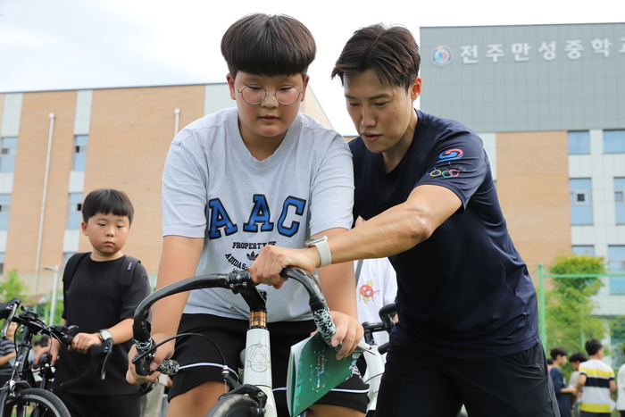LX사이클 선수단 선수가 1일 전북 전주시에서 열린 자전거 안전교육에서 지역 학생에게 올바른 자전거 탑승법을 지도하고 있다. (사진=한국국토정보공사)