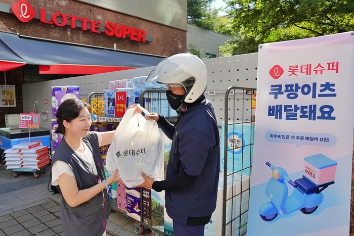 지난 4일(금) 서울시 송파구에 위치한 롯데슈퍼 신천점에서 롯데슈퍼 직원이 배달 기사에게 주문 상품을 전달하고 있는 모습. 〈자료 롯데슈퍼〉