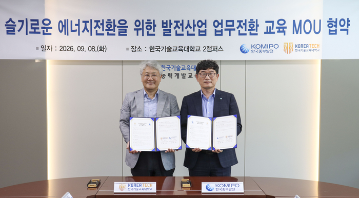 오영철 한국중부발전 친환경발전처장(오른쪽)과 이규만 한국기술교육대 산학협력단장(왼쪽)이 협약서를 작성한 후 촬영을 하고 있다. (사진=한국중부발전)