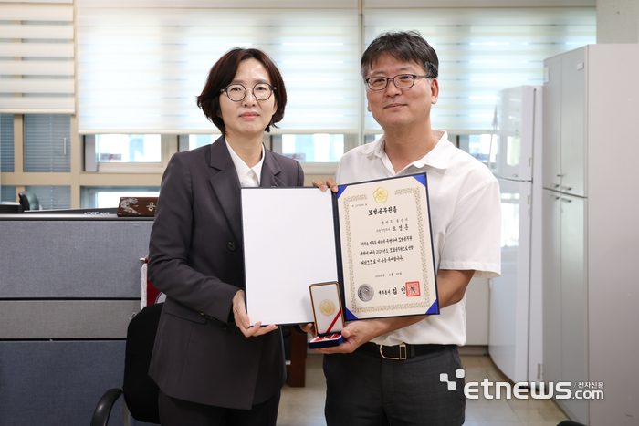 15일 오경훈 용인시 언론행정팀장(오른쪽)이 이현정 시 공보관으로부터 국무총리상과 모범공무원증을 전달받고 기념 촬영했다. 용인시 제공.