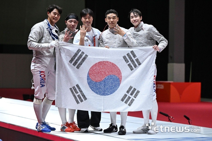 2026 아이치·나고야 아시안게임 펜싱 남자 사브르 단체전에서 4연패를 달성한 대한민국 대표팀 선수단이 국민 응원 메시지가 담긴 태극기를 들고 기념 촬영을 하고 있다.