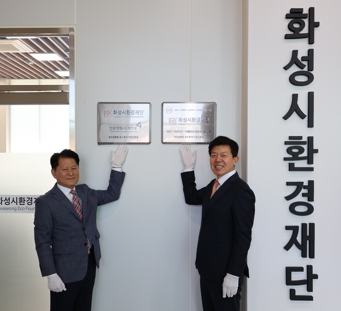 중소벤처기업인증원 엄진엽 원장(왼쪽), 화성시환경재단 정승호 대표이사가 ISO 14001(환경)·45001(안전보건)·37001(부패방지) 및 HRMS(인권경영) 인증 수여식에서 인증 현판 부착 후 함께 기념촬영을 하고 있다.