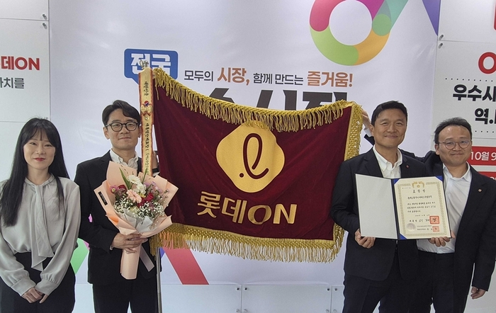 김장훈 롯데온 상무(오른쪽 두번째)가 임직원과 함께 지난 9일 충청남도 공주시 아트센터 고마에서 열린 '2026년 전통시장 및 상점가 활성화 유공 포상'에서 대통령 표창 기념 사진을 촬영하고 있다. 〈자료:롯데온〉