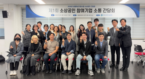 '2026년 상품개선 지원사업 참여 소상공인 소통 간담회'에 참가한 관계자들이 기념촬영을 하고 있다.