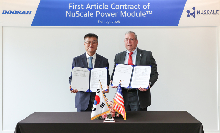 29일 창원 본사에서 열린 계약 체결식에서 뉴스케일파워 칼 피셔 COO(사진 오른쪽)와 두산에너빌리티 김종두 사장이 기념 촬영하고 있다. 두산에너빌리티 제공