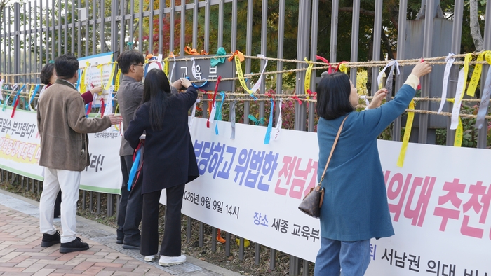 국립목포대학교 교수들이 10월 30일 교육부 앞에서 전남 국립의과대학 후보대학 선정의 공정성과 투명성을 촉구하며 희망 리본을 달고 있다.