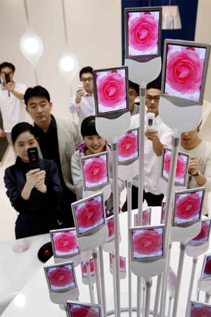  삼성SDI 직원들이 세계 최초로 양산한 AM OLED로 ‘전자화단’을 만들고 휴대폰으로 촬영하며 즐거워하고 있다.